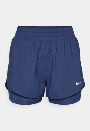 Marineblå sportsbukser i dobbeltlag med elastisk talje og hvid Nike swoosh-logo på forsiden til højre.
