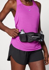 Czarny pas nawadniający z dwoma szarymi butelkami na wodę, noszony na różowym sportowym tank topie i czarnych szortach, wyposażony w elastyczne przegrody.