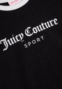 Černé bavlněné tričko s bílým logem "Juicy Couture SPORT." Límec je bílý, což kontrastuje s látkou.