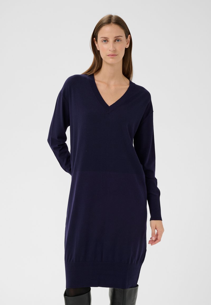 Marineblaues Strickkleid mit V-Ausschnitt, langen Ärmeln und geripptem Saum. Hergestellt aus weichem Material, mit lockerem Schnitt und minimalistischem Design.