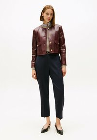 Bordeaux leren cropped jack met gouden knopen, een grijze trui eronder, marineblauwe op maat gemaakte broek en zwarte pointed-toe hakken.