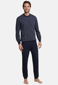 El conjunto de pijama de estampado de marina incluye una parte superior de manga larga con puntos blancos y pantalones ajustados a juego, confeccionados con una tela suave, diseñados para brindar comodidad.