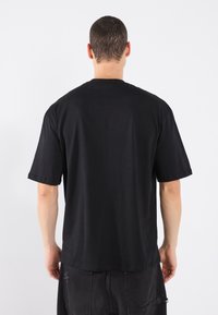 Black cotton t-shirt with short sleeves, a round neckline, and a relaxed fit. Minimalist design, no visible patterns or logos.