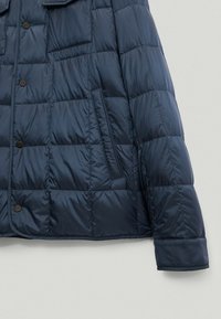 Granatowa kurtka puchowa z pikowanym wzorem, zatrzaskami i boczną kieszenią. Wykonana z gładkiego, błyszczącego materiału o lekkim wykończeniu.