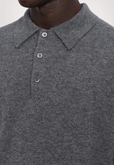 Graues, gestricktes Polohemd mit umgeschlagenem Kragen, ausgestattet mit drei grauen Knöpfen. Nahaufnahme der Stofftextur und der Knopfdetails.