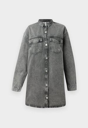 Grijze denim jurk met lange mouwen, knoopsluiting aan de voorkant, twee borstzakken en een afgeronde zoom. Bevat een subtiele vervaagde textuur en metalen knopen.
