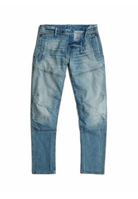 Siniset farkut, joissa on tilkkutyökuvio erivärisin sinisin sävyin, useita taskuja ja erivärisiä ompeleita.