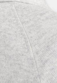 Tissu en tricot gris avec une apparence texturée, présentant un motif lisse et subtil ainsi qu'un léger éclat près de la zone du col.