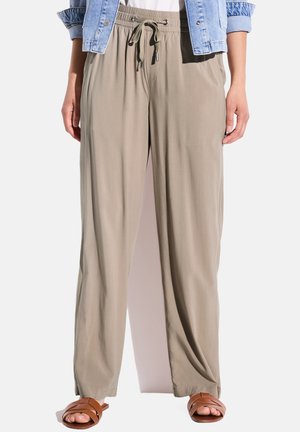 Leichte, beigefarbene, weit geschnittene Hosen mit einem Gummizugbund, glatter Textur und einem entspannten Schnitt. Kombiniert mit braunen Sandalen.