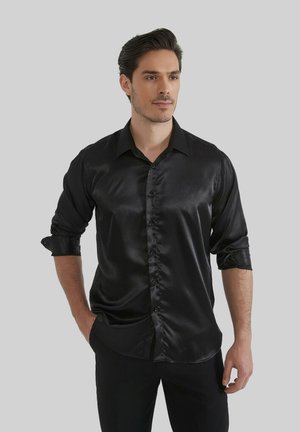 Chemise en satin noir avec un col classique, un devant à boutons et des manches retroussées, présentant une texture lisse et brillante.