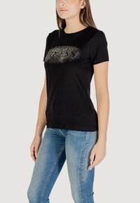 T-shirt nera in cotone, con scollatura rotonda e maniche corte, decorata con un logo "GUESS" in strass.