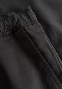 Gros plan sur un pantalon taille élastique noire montrant la texture du tissu et les coutures de la couture latérale.