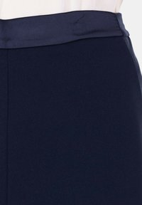 Gonna blu navy caratterizzata da una texture liscia, un ampio elastico in vita e linee pulite, progettata per una vestibilità slim senza chiusure visibili.