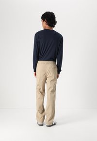 Navy long-sleeve shirt paired with khaki elastic waist trousers. Trousers feature a back pocket and are made of lightweight fabric.