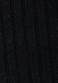 Tessuto nero con texture che presenta motivi rigati verticali, realizzato in materiale a maglia, con una superficie morbida e colorazione uniforme.