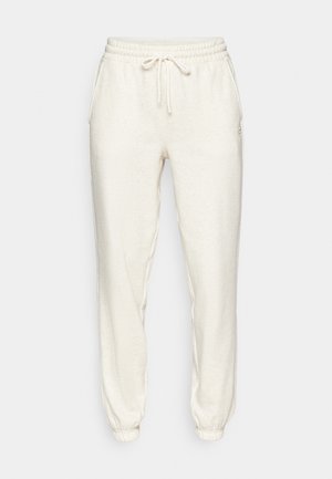 Lys beige joggebukser laget av mykt stoff, med elastisk midje med snor, sidelommer og ribbestrikkede ankler.