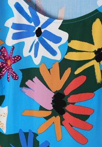 Tessuto con motivo floreale colorato che presenta grandi fiori blu, gialli e rossi su uno sfondo blu, con una base verde e una consistenza liscia.