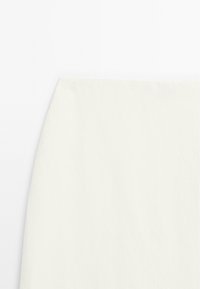 Weißer Stoff mit weicher, plüschiger Textur, nah aufgenommen auf einer flachen Oberfläche mit dezenten Schatten und Falten.