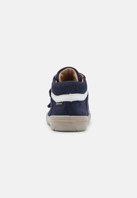 Scarpa alta in suede blu navy con striscia bianca accentata, fodera in beige e suola in gomma testurizzata. Presenta un'etichetta con il marchio sul lato.