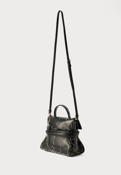 Black leather crossbody bag with top handle, featuring a structured shape and white stitching accents. Adjustable strap for versatility.