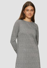Langarmkleid im schwarz-weißen Hahnentritt-Muster, aus strukturiertem Stoff gefertigt, mit rundem Ausschnitt und lässiger Passform.