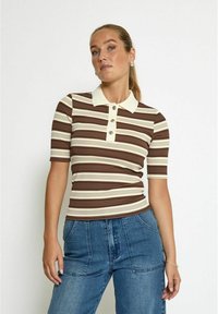 Brun och gräddfärgad randig polo t-shirt med korta ärmar, med en knappslå och ribbad textur. Bärs med blå denimbyxor.