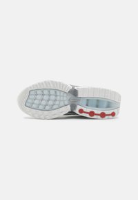 Grijze sport schoen zool met een gestructureerde witte rubberen onderkant, transparante secties en drie rode ronde accenten.