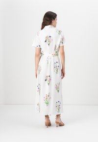 Floral print maxi dress with short sleeves, white fabric, belted waist, features multiple colorful flower patterns throughout.