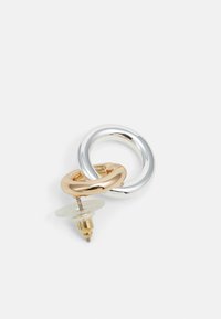 Two interlinked hoop earrings in silver and gold-tone metal. Features a clear plastic backing and a polished finish.