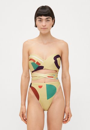 Trägerloser, gelber Bikini mit geometrischen Mustern in Rot, Grün und Blau. Hochgeschnittene Unterteile mit einem gewickelten Design in der Mittelpartie.