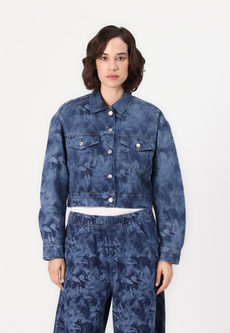 Kort denimjacka i mörkblått med blommönster, med knäppning framtill, två bröstfickor och långa ärmar.
