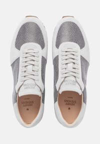 Weiße und graue Sneaker mit Mesh-Einsätzen und Wildleder-Akzenten. Merkmale sind runde Schnürsenkel, eine strukturierte Sohle und geprägtes Branding im Inneren.