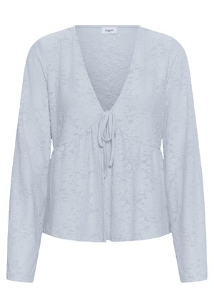 Blouse à manches longues bleu clair avec texture jacquard florale, col en V profond et fermeture à nouer sur le devant, étiquette "Saint" au niveau du col.