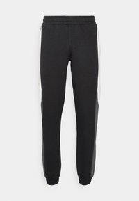 Pantalones de chándal negros con puños ajustados, que cuentan con paneles laterales blancos en contraste, cinturilla elástica y textura suave. Adecuados para un uso casual.