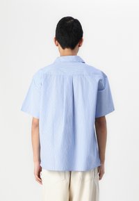 Chemise à manches courtes bleu clair avec de fines rayures blanches, dotée d'un col étalé et d'un pli dans le dos pour plus de liberté de mouvement.