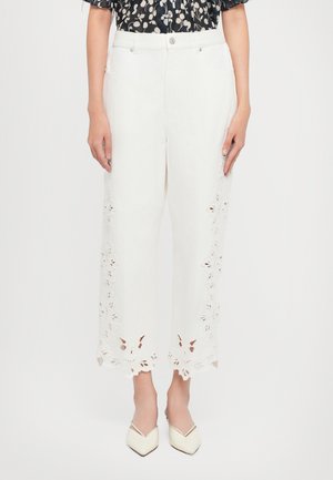 Witte wijde broek met geborduurde bloemen uitsparingen aan de onderkant. Gemaakt van lichte stof met een knoopsluiting en voorkruiden.
