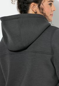 Ciemnoszary hoodie z kapturem na sznurki, z teksturowanym materiałem i widocznymi detalami st stitching na szwach i ramionach.