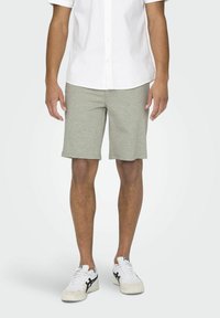 Grijze katoenen shorts met een rechte snit, gecombineerd met een wit overhemd met knopen en witte sneakers met zwarte accenten.