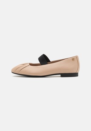 Ballerines en cuir beige avec un détail de bout froncé et une bride élastique noire sur le coup de pied. Semelle en caoutchouc noire basse.