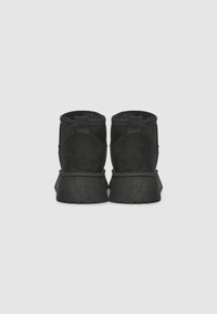 Bottines noires en suède avec une finition texturée, dotées d'un bout arrondi et d'une semelle en caoutchouc surélevée et robuste.
