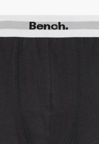 Boksarske hlače temno sive barve iz bombaža z belim elastičnim pasom, ki ima sive poudarke. Na pasu je natisnjen črn logo "Bench."