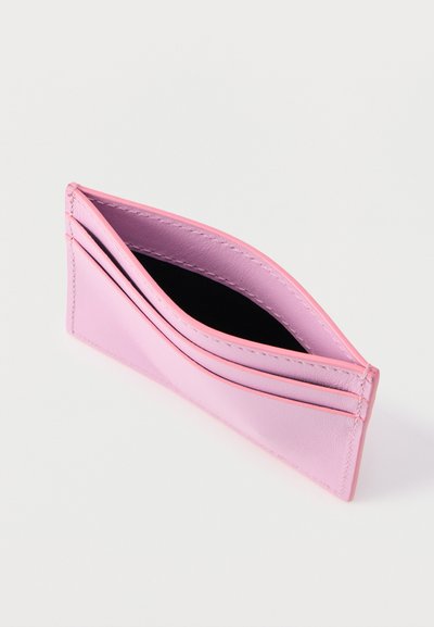 Πορτοφόλι θήκη καρτών από ανοιχτό ροζ δέρμα με πολλαπλές θέσεις για κάρτες και μία κεντρική θήκη, σε κεκλιμένη όψη σε λευκό φόντο.