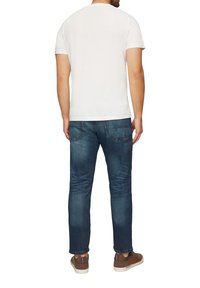 T-shirt blanche à manches courtes, en coton, décolleté rond, associée à un jean en denim bleu, coupe régulière, avec poches cousues et décoloration.