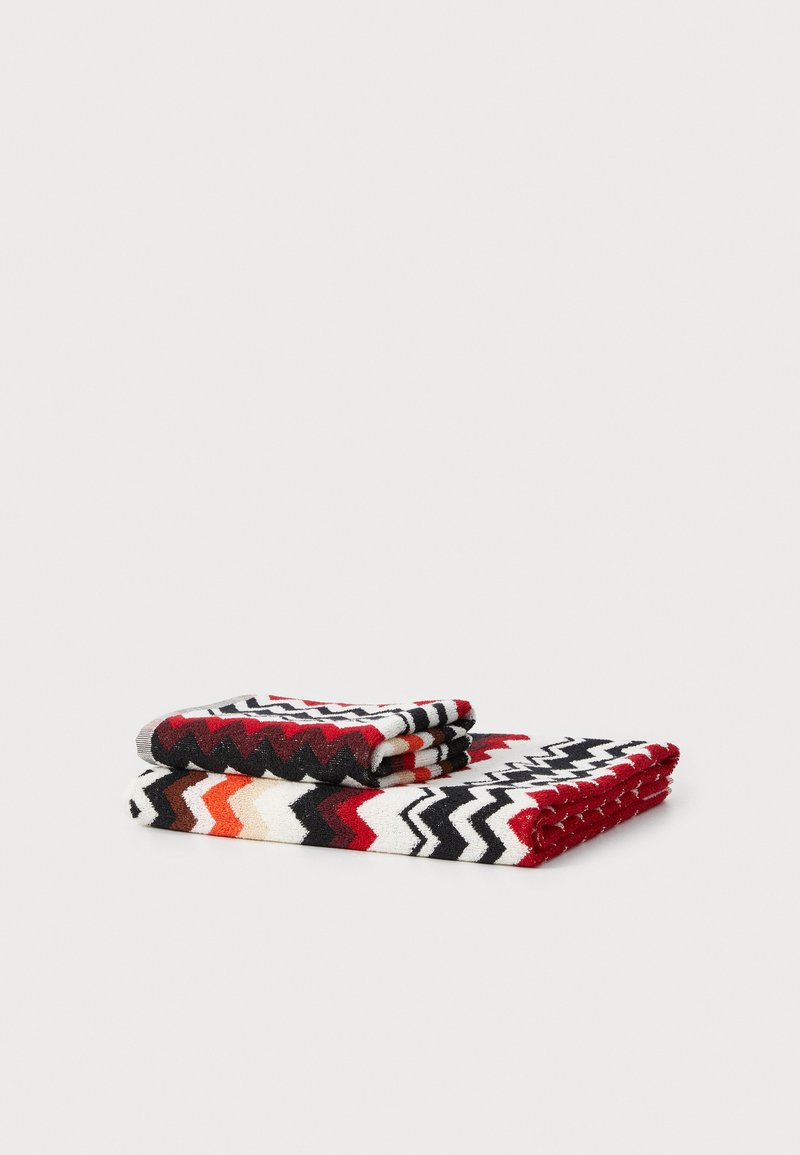 Bombažna brisače zložene, z značilnim zig-zag vzorcem v rdeči, črni, beli in oranžni barvi, ki prikazuje teksturirano površino in živahen dizajn.