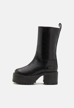 Black leather ankle boots with a block heel, featuring a textured rubber sole and a rounded toe. Includes a pull tab for easy wear.