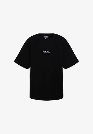 T-shirt nera oversize in cotone con maniche corte. Presenta una stampa bianca con la scritta "CHICAGO RAW MUSIC SCENE" sul petto.
