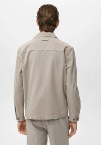 Light gray jacket made of smooth fabric, featuring a classic collar, buttoned cuffs, and a simple back yoke design.