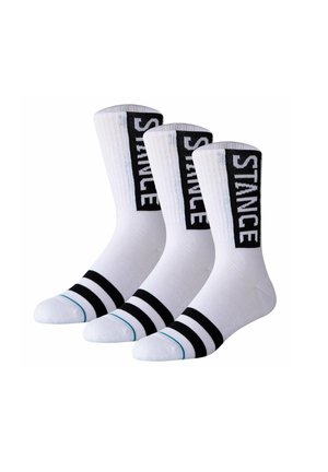 Drei weiße Crew-Socken mit zwei schwarzen Streifen in der Nähe der Zehen und "STANCE" vertikal auf schwarzen Bändern entlang der Wade geschrieben.