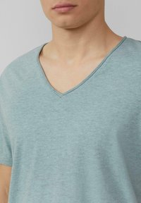 Jasnoniebieska koszulka z dekoltem w serek, wykonana z miękkiego materiału. Koszulka ma gładką teksturę i krótkie rękawy, z delikatnym melanżowym wzorem.