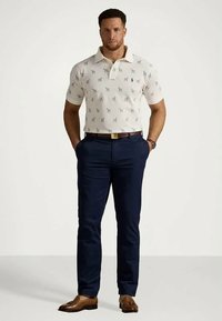 Πολυέλαιο μπλουζάκι με κοντό μανίκι σε κρέμα απόχρωση με διακριτό σχέδιο, συνδυασμένο με σκούρα μπλε παντελόνια και καφέ λουστρίνια. Κλασικό γιακά και εφαρμοστή γραμμή.